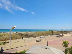 Blick auf einen Strand mit sandigem Ufer, einigen Bänken und einem Zaun.