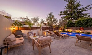 An outdoor patio area with a pool, seating arrangements, and a wooden fence. - Villa di Capaka Private Pool (Rethymno)