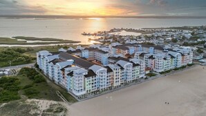 Un hotel costero con edificios de varios pisos, acceso directo a la playa y vistas al atardecer.