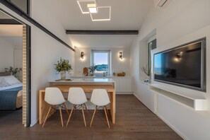 Eine moderne Küche mit Essbereich, einem großen Fernseher und Blick ins Freie.