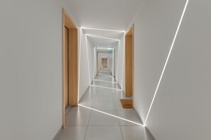 Ein moderner Flur mit geometrischen Lichtmustern, Holztüren und einem gefliesten Boden.