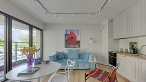 A modern kitchen with white cabinets, a dining area with a white table and chairs, and a large window with a view of the outside. - Żeromskiego 23 by Grand Apartments (Gdynia)
