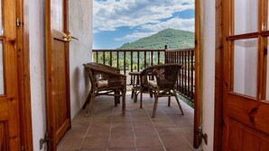 Ein Balkon mit Korbmöbeln und Blick auf eine Hügel.