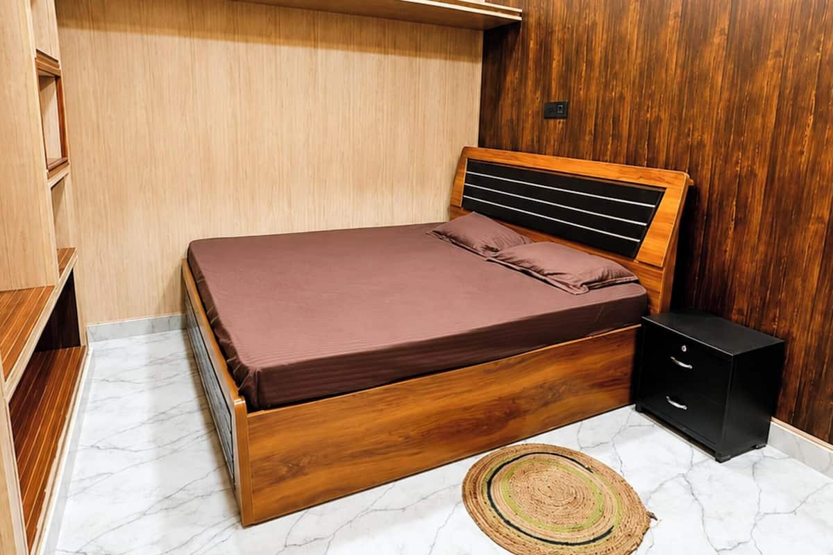 Un dormitorio con una cama de madera, una mesita de noche, un armario empotrado y una lámpara en el techo.