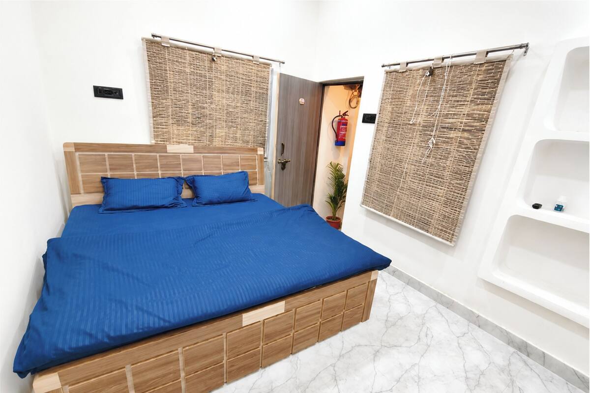 Una cama con colcha azul, cabecera de madera y suelo de mármol blanco.