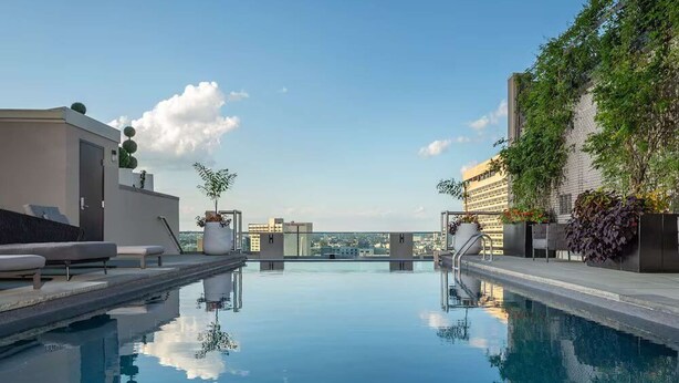 Una piscina sul tetto con cielo sereno, vista sulla città e architettura moderna.