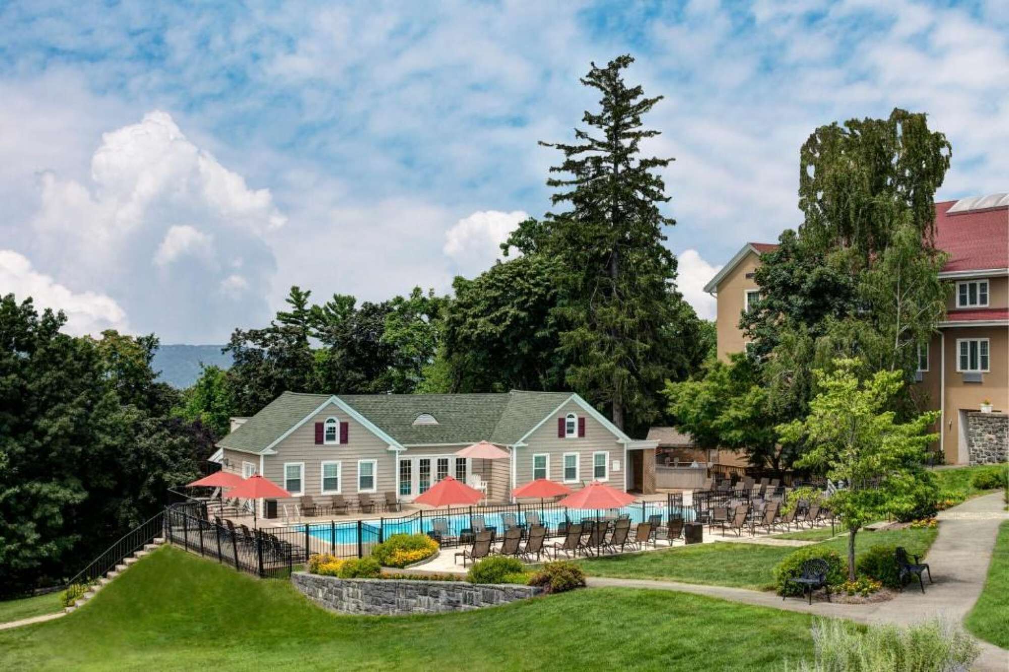 Un hôtel doté d’une piscine, d’un espace extérieur aménagé avec des sièges et d’un escalier menant à l’entrée.