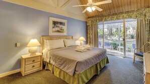 A bedroom with a bed, two bedside tables with lamps, a ceiling fan, a window with curtains, and a view of the outdoors. - Near the Beach with Pool, Hot Tub & Full Kitchen (Hilton Head)
