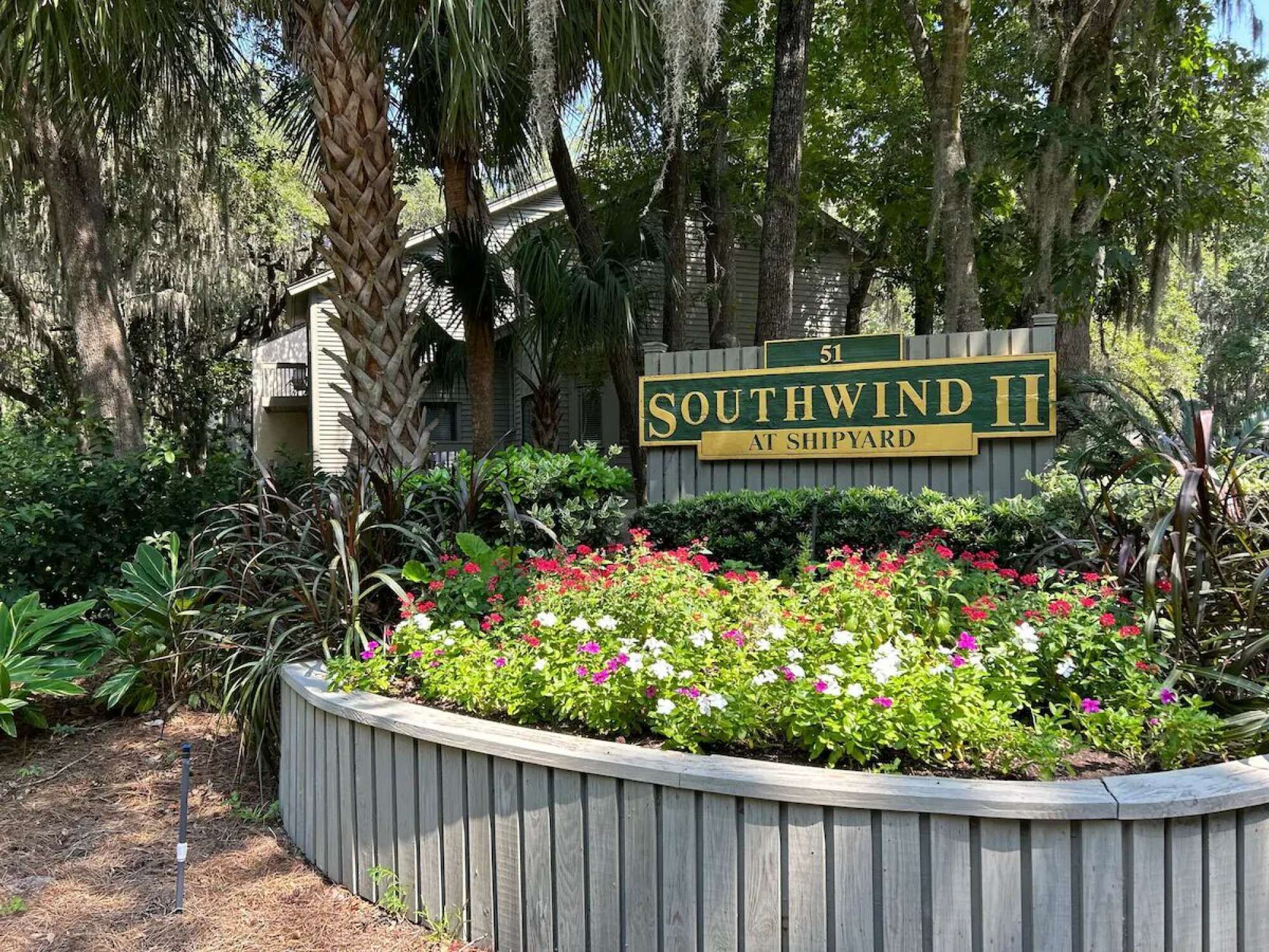 Letrero de Southwind II en Shipyard, rodeado de un jardín ajardinado con diversas plantas y flores.