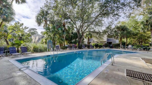 A swimming pool with lounge chairs and a signboard.