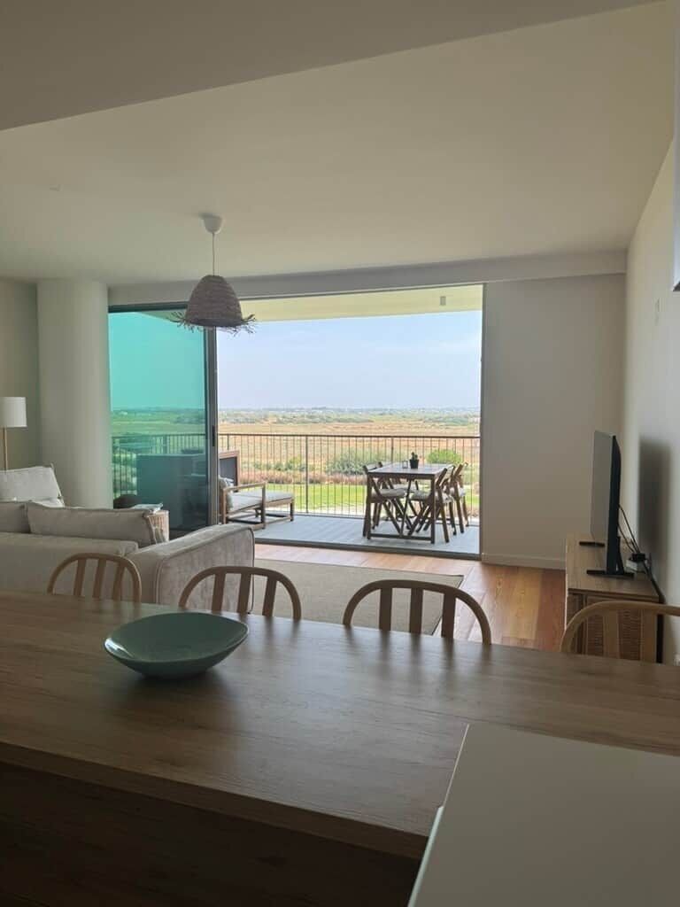 Un salon moderne comprenant un coin repas, un téléviseur et un balcon avec vue.