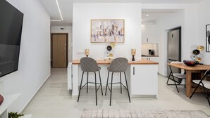 A modern kitchen with a central island, two bar stools, and a dining table with chairs. - Spacious luxury 2BR flat - Pagrati sq. (Athens)