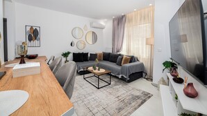 A modern living room with a sofa, coffee table, and a flat-screen TV. - Spacious luxury 2BR flat - Pagrati sq. (Athens)