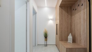 A hallway with a wooden bench, a small potted plant, and a decorative lantern. - Spacious luxury 2BR flat - Pagrati sq. (Athens)