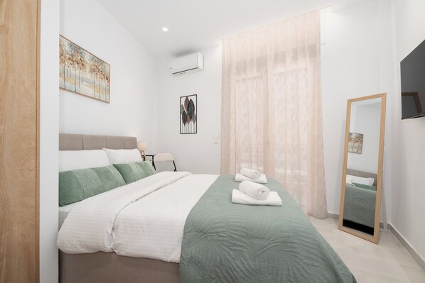 Quarto bem arrumado com uma cama, mesa de cabeceira, espelho e obras de arte nas paredes.