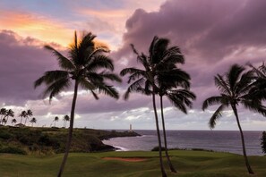 A golf course with palm trees, a lighthouse, and the ocean. - Prince Kuhio 108 - Spacious, A/C, close to beach (Koloa)