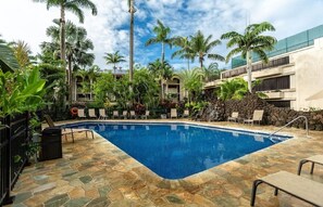 A swimming pool with stone tiles, surrounded by palm trees and lounge chairs. - Prince Kuhio 108 - Spacious, A/C, close to beach (Koloa)
