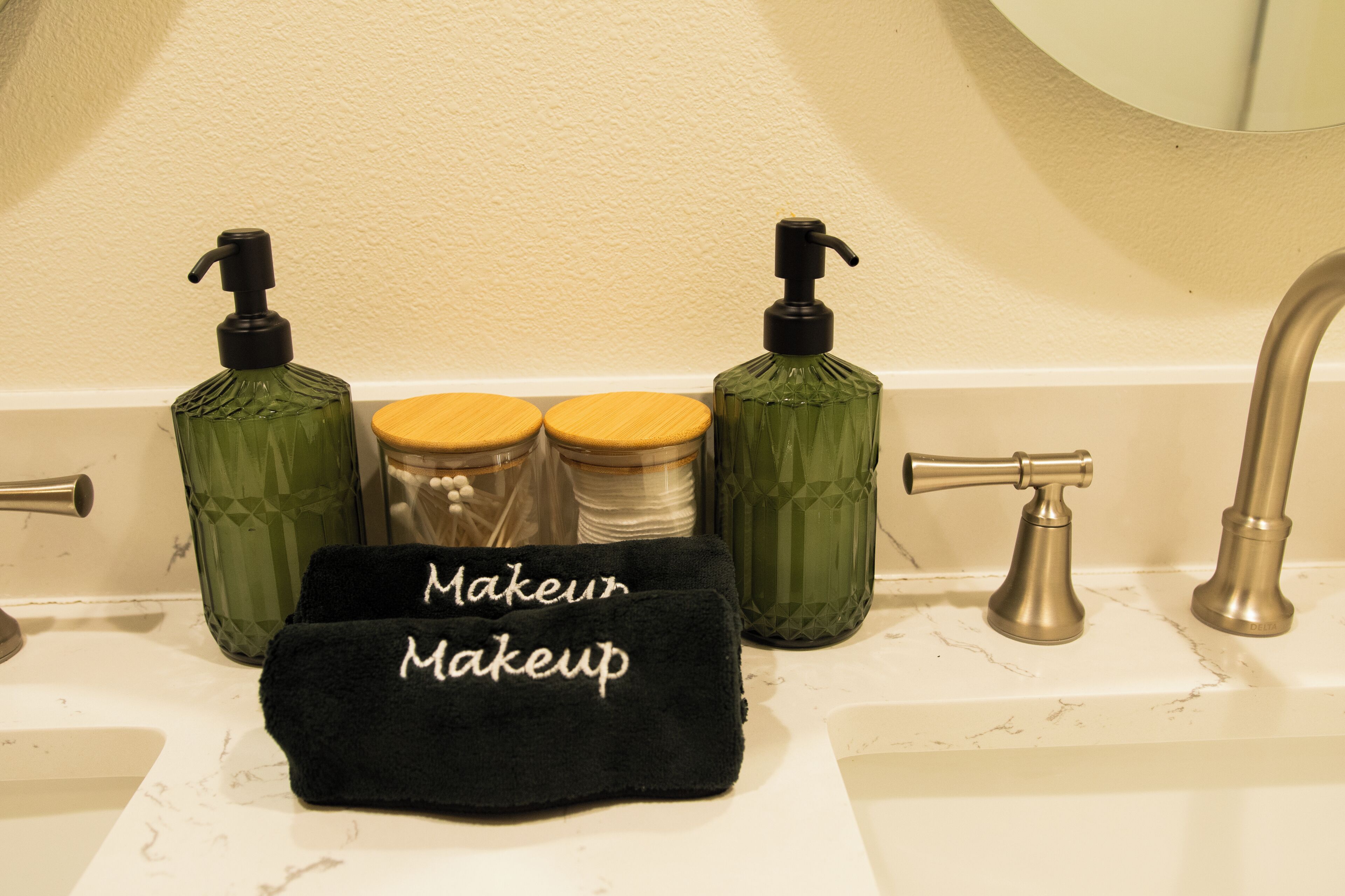 A bathroom vanity with a mirror, two soap dispensers, a towel rack, and a sink.