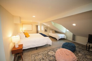Un dormitorio con cama, mesita de noche, lámpara y reposapiés.