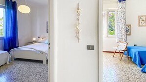 Ein Schlafzimmer mit Bett, Nachttisch, einer Hängelampe, einer Wanddekoration mit Sternen und einem Fenster mit blauen Vorhängen.