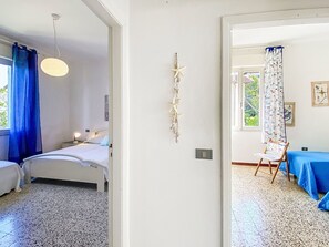 A bedroom with a bed, a nightstand, a hanging light fixture, a wall-mounted star decoration, and a window with blue curtains.