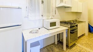 Eine kompakte Küche mit weißem Kühlschrank, Mikrowelle, Gasherd und Backofen.