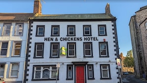 Un edificio de dos pisos con un letrero que dice 'HEN & CHICKENS HOTEL' en la parte superior.