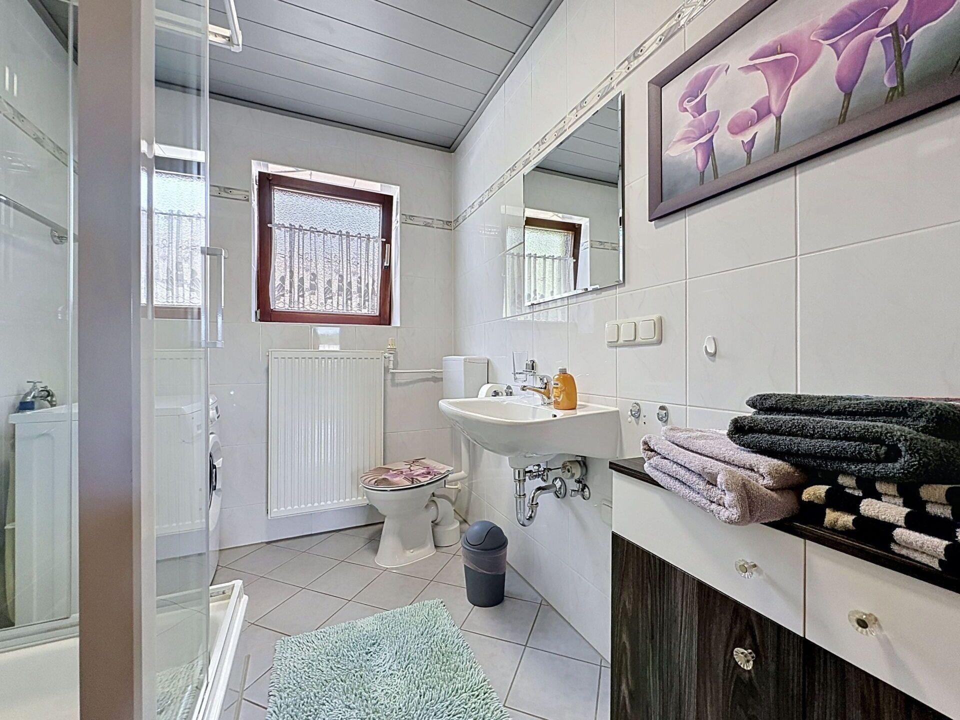 Une salle de bain équipée d’une douche, de toilettes, d’un lavabo et d’un miroir.