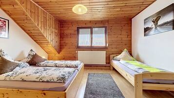 Ein Holzinnenraum mit Schlafkoje, einer Couch, einer Heizung und einem Fenster.
