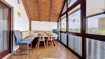 Ein Zimmer mit Holzboden, einem Tisch mit Stühlen, einer Couch und großen Fenstern mit Blick.