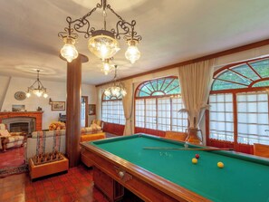 Ein Billardraum mit Pooltisch, Kamin und großem Fenster mit Aussicht.