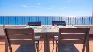 A table set for two with chairs, a view of the sea, and a balcony railing. - Stunning private villa for 4 people with TV and terrace (Castelsardo)