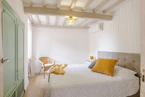 Ein Schlafzimmer mit einem Bett, einem Sessel, einem Nachttisch mit Lampe und einem fest installierten Heizkörper.
