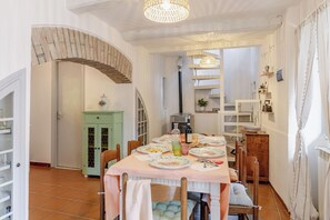 Ein Essbereich mit einem Tisch für vier Personen, einem grünen Schrank und einer Treppe, die in einen anderen Raum führt.