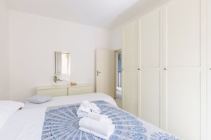 Una camera da letto con un letto, un comodino con uno specchio, un armadio e un bagno visibile attraverso una porta aperta.