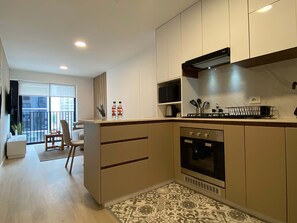 A modern kitchen with a built-in oven, a microwave, and a gas stove. There is a dining area with a chair and a small table. - w Serene Stay 2BR in San Isidro (Lima)