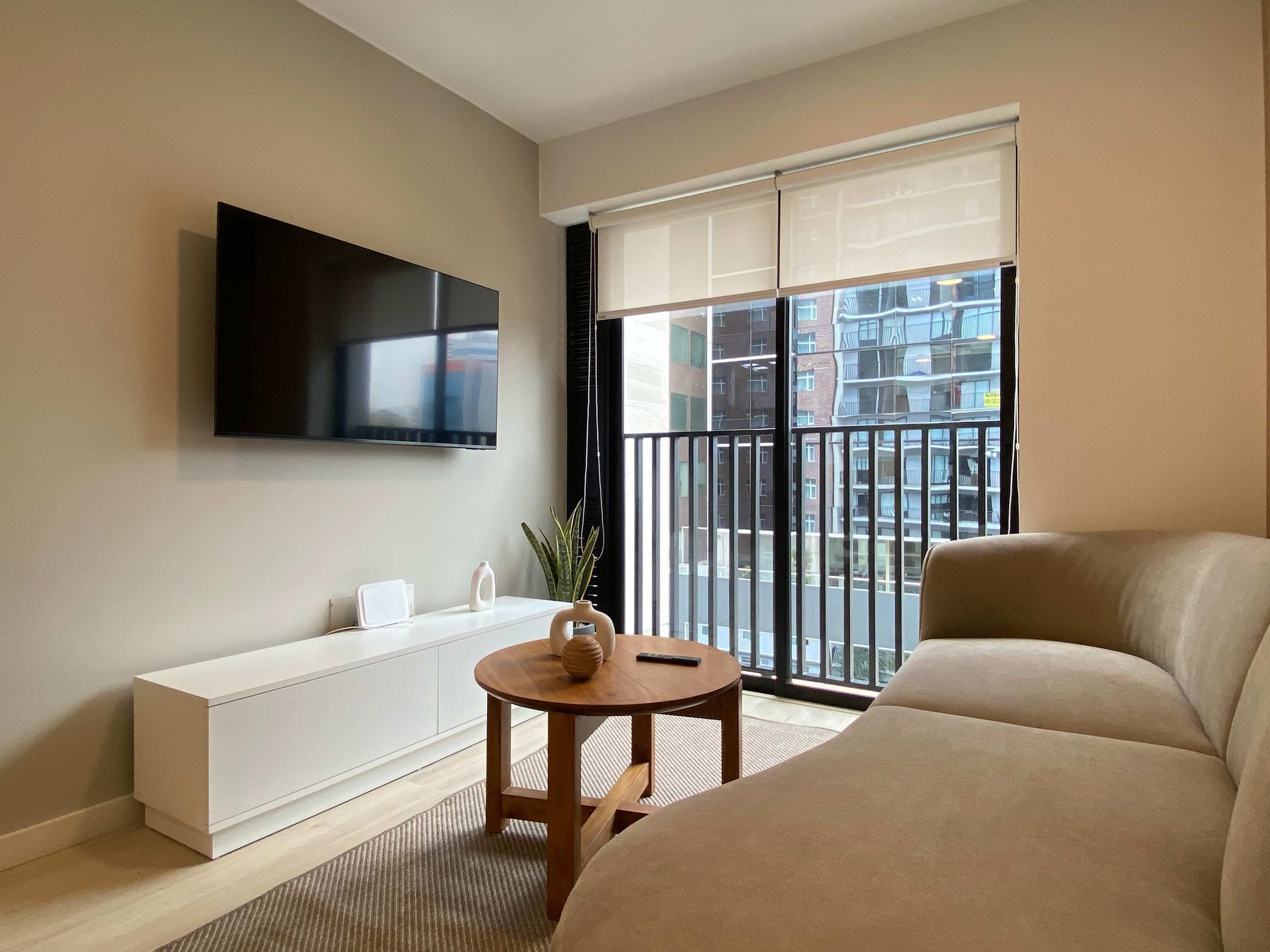 A modern living room with a flat-screen TV, a sofa, a small round table, and a radiator.