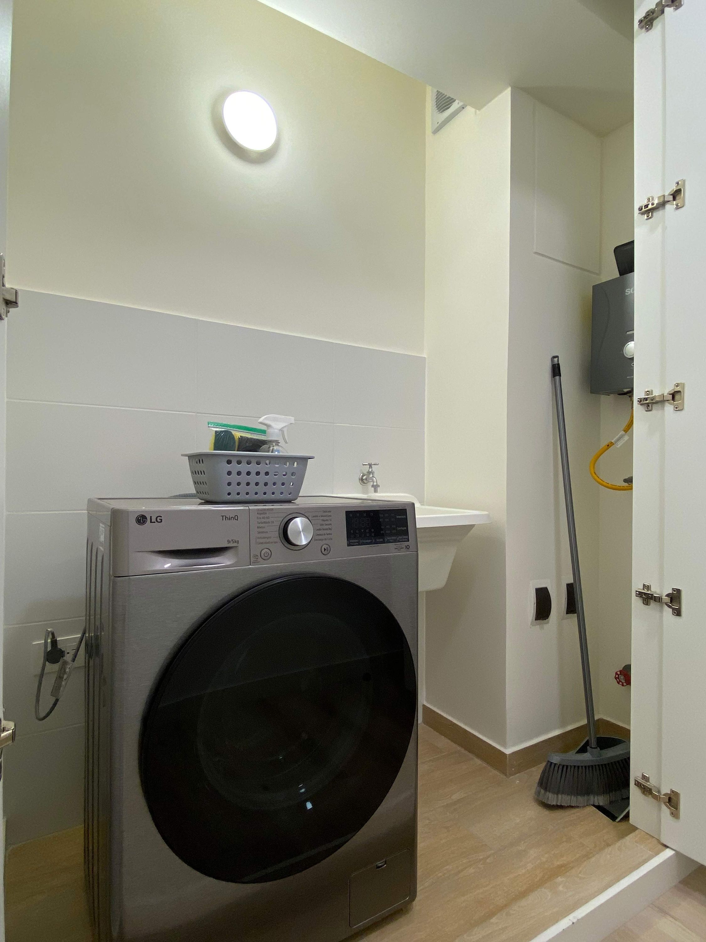 Un espace buanderie équipé d’un lave-linge LG, d’un évier et d’un balai.