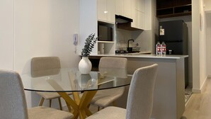 Una cocina moderna con armarios blancos, una mesa de vidrio y cuatro sillas.