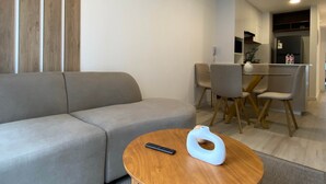 Una sala de estar moderna con un sofá, una mesa redonda de madera y un control remoto.