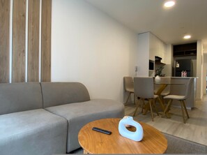 A modern living room with a sofa, a round wooden coffee table, and a remote control. - w Serene Stay 2BR in San Isidro (Lima)