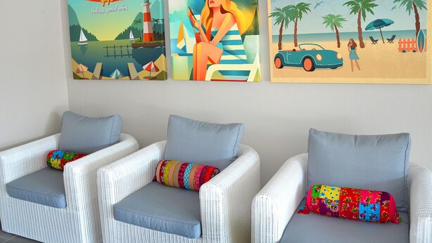 Three framed posters depicting summer scenes, two wicker chairs with cushions, and a white wall. - Stunning Holiday Home for 6 in Marseillan (Marseillan)