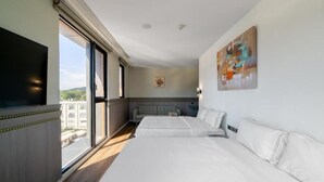 Una habitación de hotel con una cama grande, un sofá, un televisor de pantalla plana y un cuadro en la pared.