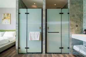 A hotel room with a bed, a bathroom with a mirror and towel rack, and a door with a towel hanging on it.