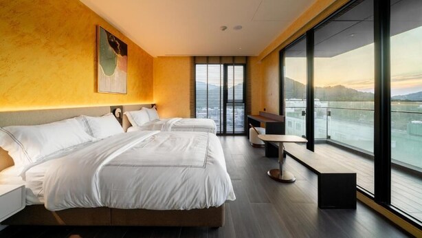 Una habitación de hotel moderna con una cama grande, un escritorio y vistas a la ciudad.