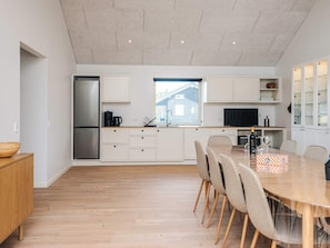 A modern kitchen with a large island, built-in appliances, and a dining area with a round table and chairs. - 5 Star Holiday Home in Ansager (Ansager)
