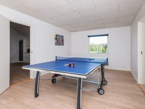 A ping pong table with wheels, a window with a view, and a door leading to a kitchen. - 5 Star Holiday Home in Ansager (Ansager)