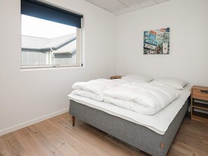 A bedroom with a bed, a nightstand, a window, and a poster on the wall. - 5 Star Holiday Home in Ansager (Ansager)