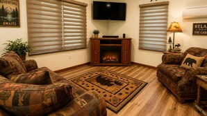 Una sala de estar con dos sofás, una chimenea, un televisor y un ventilador de techo.