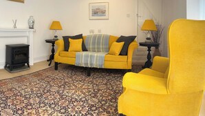Una sala de estar con sofá, sillón, chimenea y alfombra estampada.